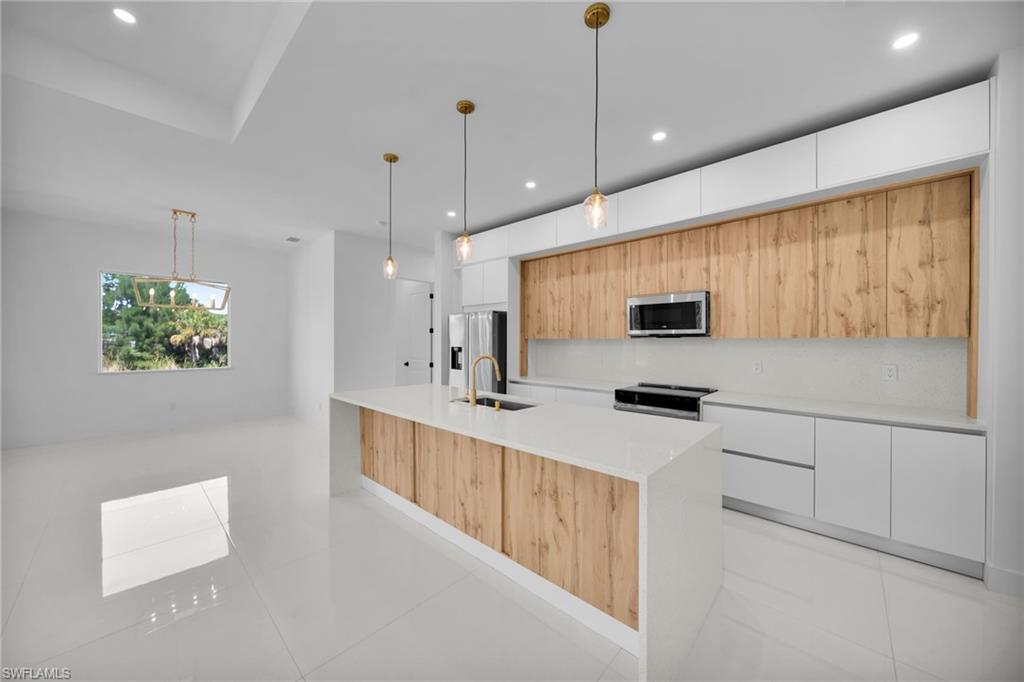 Kitchen island featuring a waterfall countertop, integrated sink, and wood-finish paneling cabinets