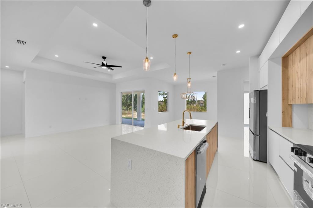 Kitchen island with a light-toned countertop, stainless steel appliances, and integrated sink