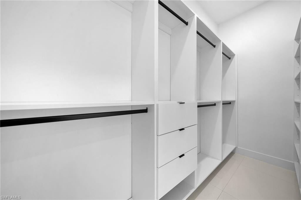 Built-in closet system featuring white shelving, integrated drawers with black pulls, and black hanging rods