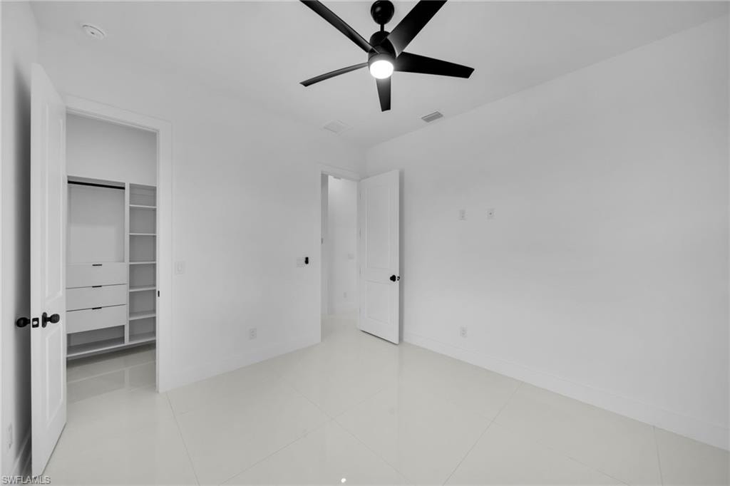 Bedroom #2: White tile flooring, custom built-in closet organization, modern black ceiling fan with integrated lighting, white interior doors, and matte black hardware