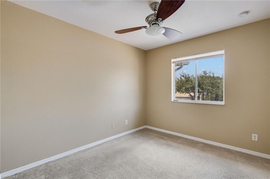 Carpeted room featuring a ceiling fan with light, and a window with white trim