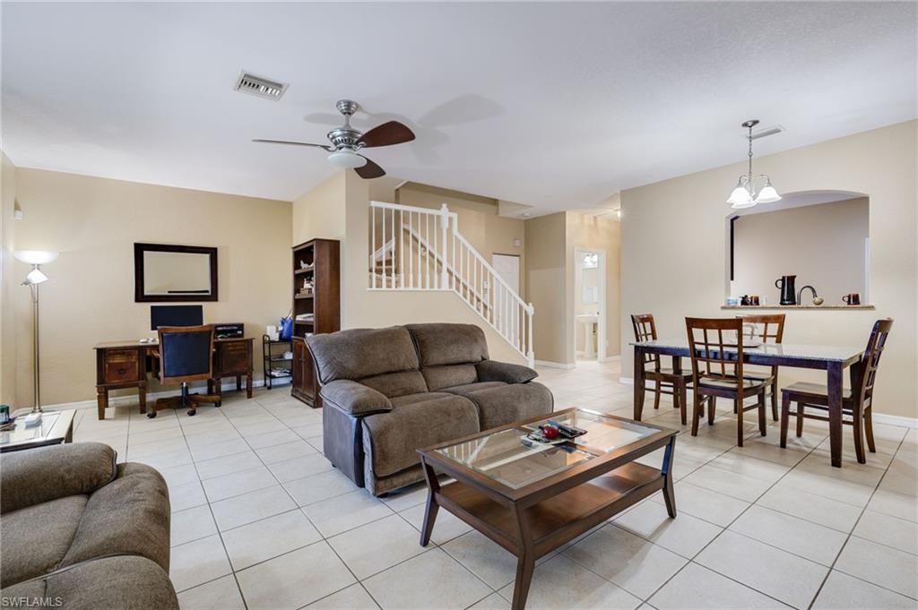 Tile flooring, ceiling fan, staircase with white railings, arched pass-through, and pendant lighting