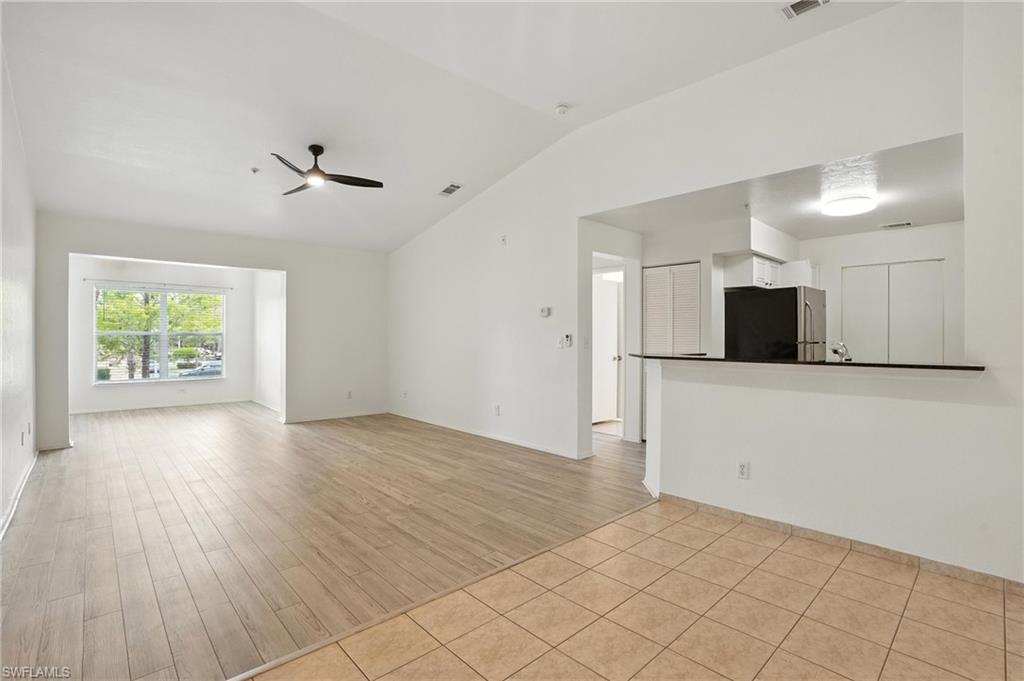 Unfurnished living room featuring vaulted ceiling, a ceiling fan, and light wood finished floors