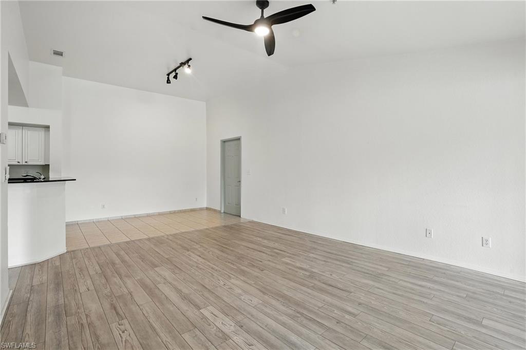 Unfurnished living room with a ceiling fan, light wood-style floors, track lighting, and high vaulted ceiling