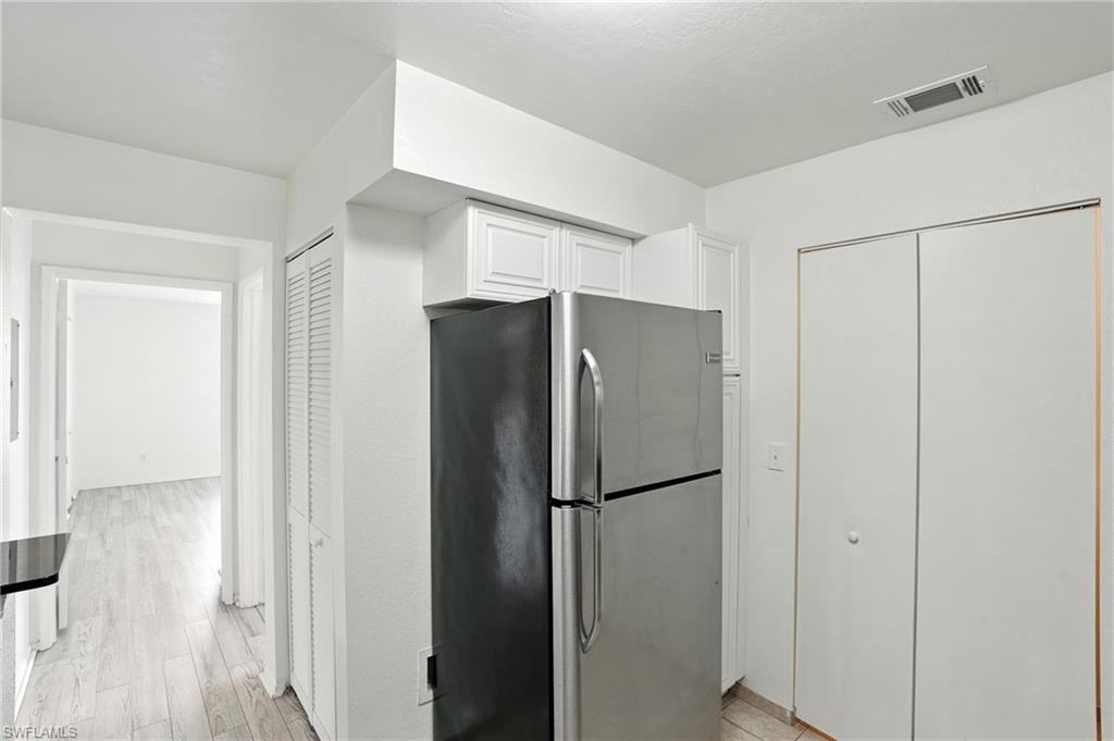 Kitchen with freestanding refrigerator, white cabinetry, and light wood finished floors