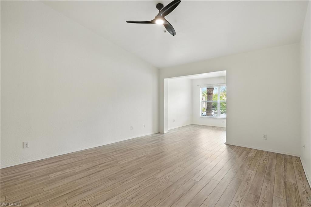 Unfurnished room with a ceiling fan, light wood-type flooring, and vaulted ceiling