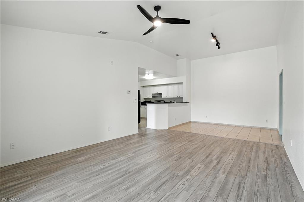 Unfurnished living room with lofted ceiling, ceiling fan, and light wood-style floors
