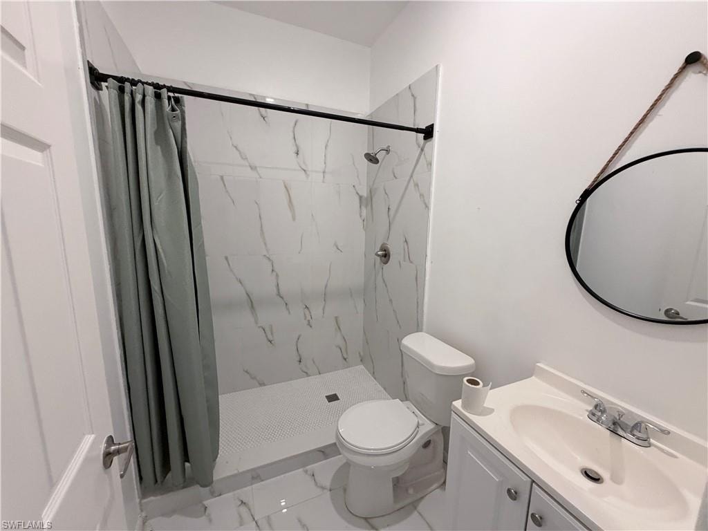 Shower with white marble-look tile surround and mosaic tile floor