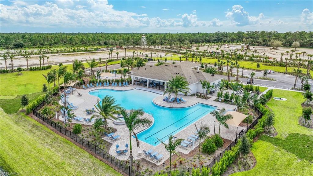 Expansive resort-style pool with integrated spa and tanning ledge, surrounded by a paved deck