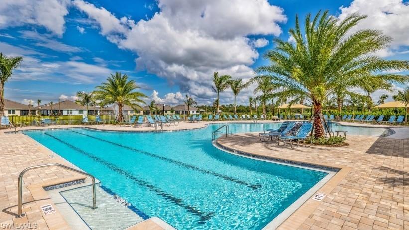 Resort-style pool with integrated lap lanes, paver deck, multiple seating areas, and mature palm trees