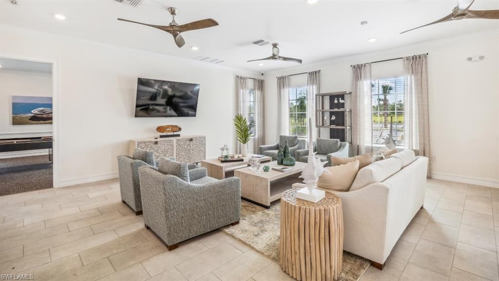 Spacious living area featuring light-toned tile flooring, multiple windows providing ample natural light, and recessed lighting with ceiling fans