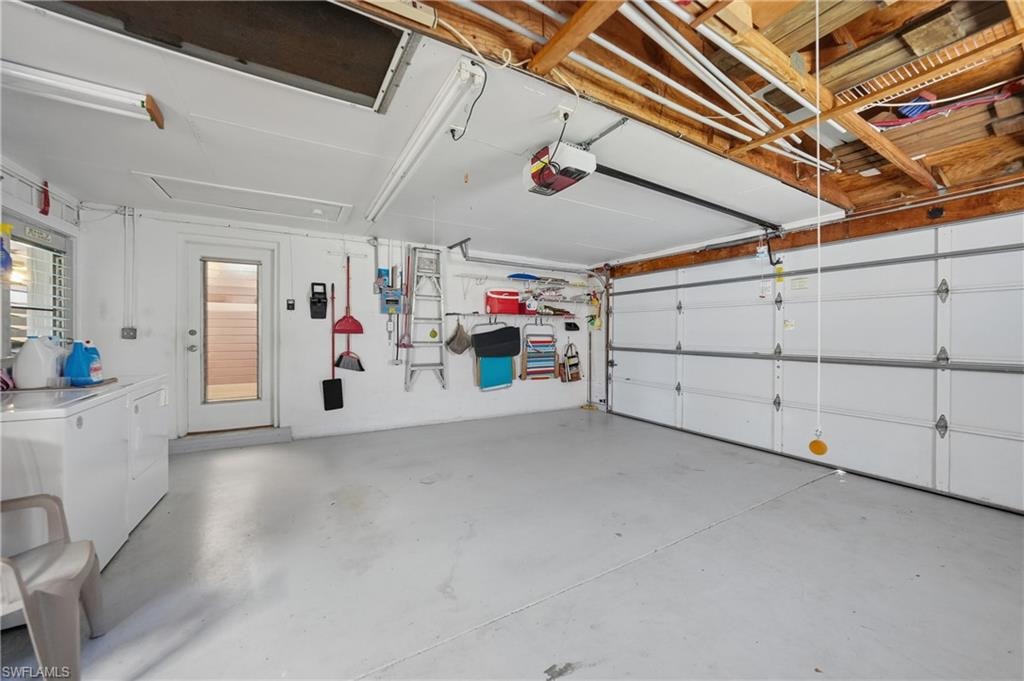 Two-car garage with concrete floor, exposed wood beam ceiling, and a built-in laundry area with appliances
