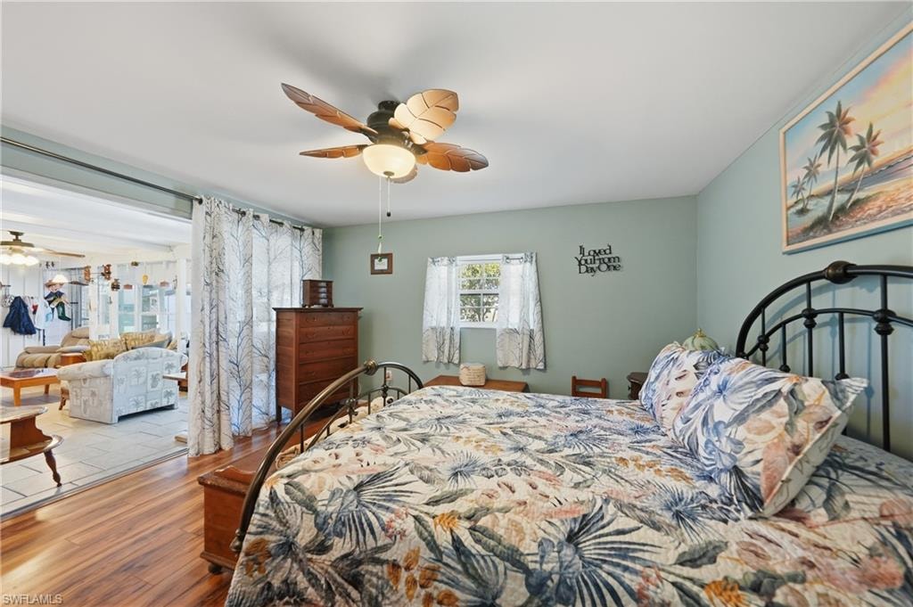Wood-finish laminate flooring with a ceiling fan featuring integrated lighting, a window with natural light, and a built-in closet