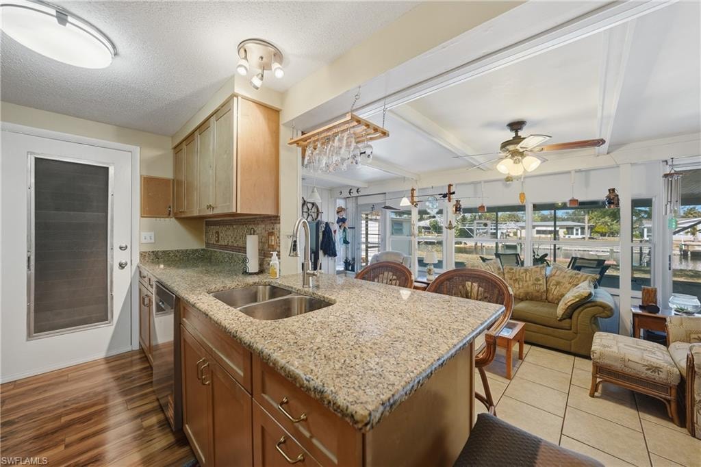 Kitchen with wood-finish laminate flooring, light wood cabinetry, and stone countertops