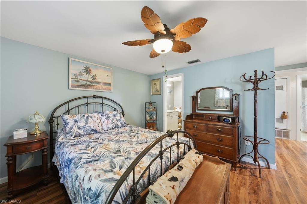 Wood-finish laminate flooring throughout, light blue walls, and a ceiling fan with leaf-shaped blades