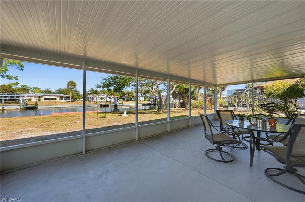 Screened outdoor living area with a solid roof, concrete flooring, and a canal with a dock