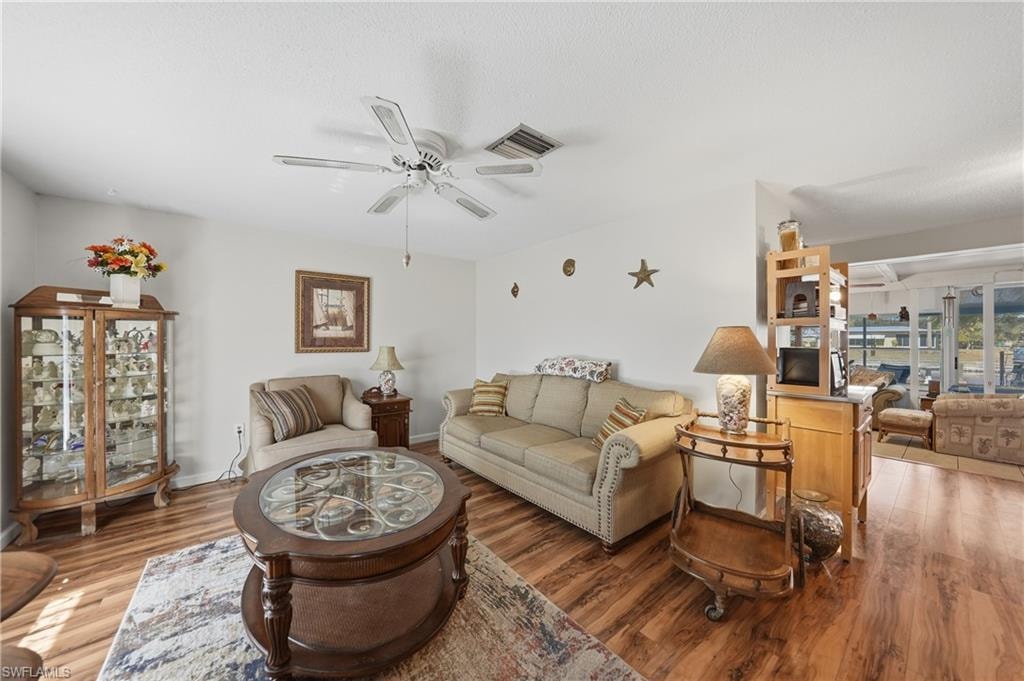 Wood-finish flooring throughout, bright white walls, and a ceiling fan with integrated lighting