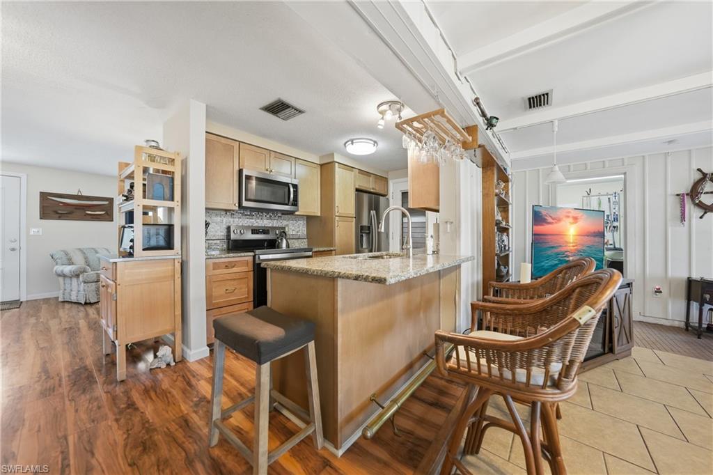 Kitchen featuring wood-finish cabinetry, granite-style countertops, stainless steel appliances, and a tiled backsplash