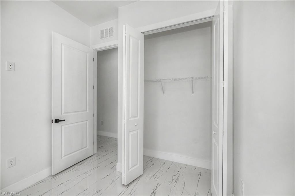 White walls, white-finish flooring, two-panel interior door, black-finish door hardware, bi-fold closet doors, wire shelving