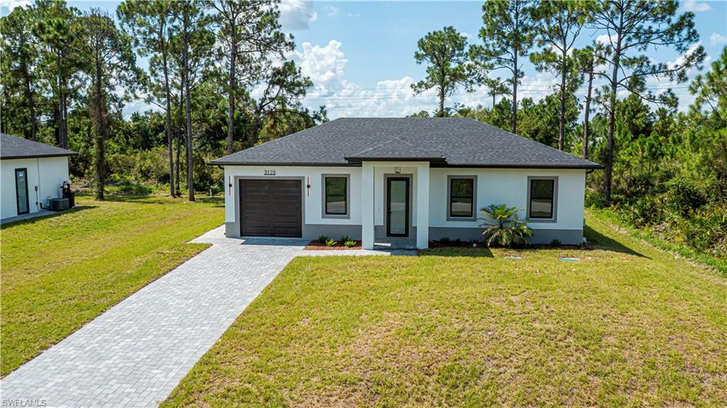 Stucco exterior with a dark shingle roof and a paver driveway