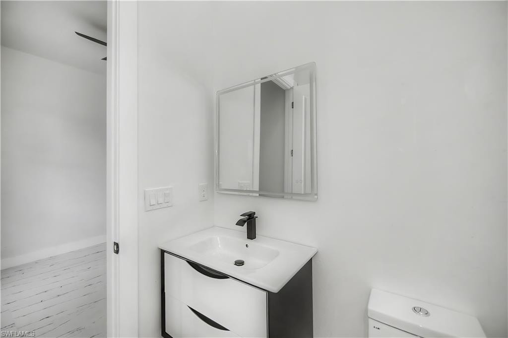 White vanity with integrated sink, black faucet, and mirrored medicine cabinet