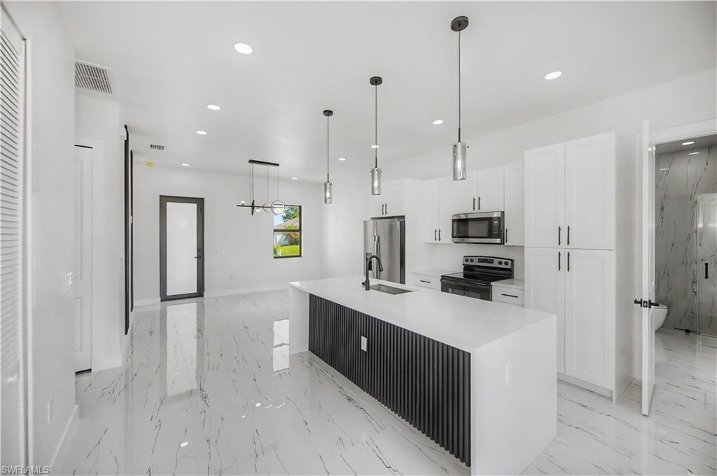 Spacious open-concept kitchen featuring white shaker cabinetry, stainless steel appliances, and a central island with a quartz countertop