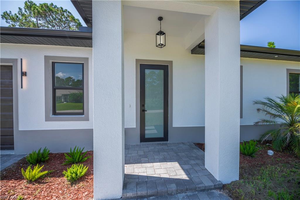 Modern exterior with white stucco finish, dark framed windows, and a glass-paneled entry door