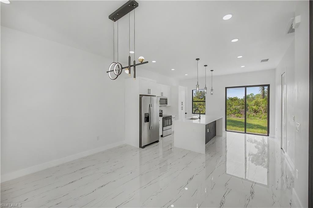 Open-concept living space featuring white marble-look flooring, recessed lighting, and a modern chandelier