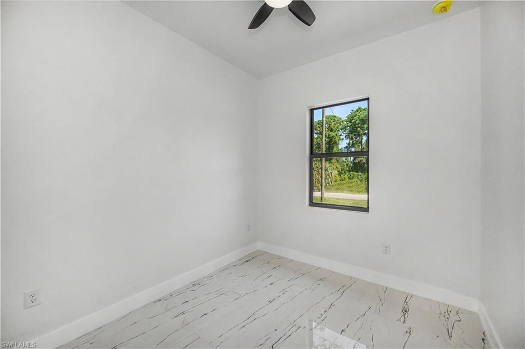 White walls, window with dark trim, ceiling fan, recessed lighting, and white tile flooring with dark veining