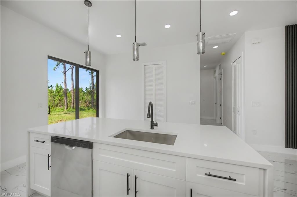 Kitchen island with a white countertop and integrated sink, stainless steel dishwasher, and three pendant lights