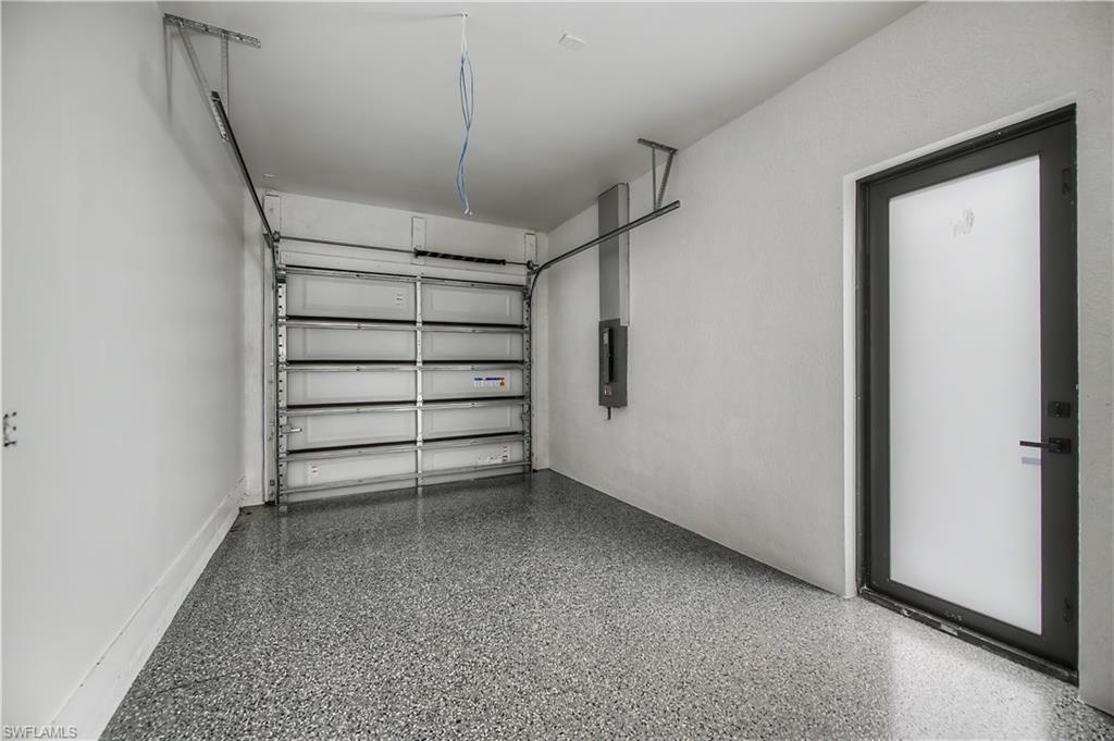 Attached garage featuring a segmented overhead door, epoxy floor, and a frosted glass-paneled entry door