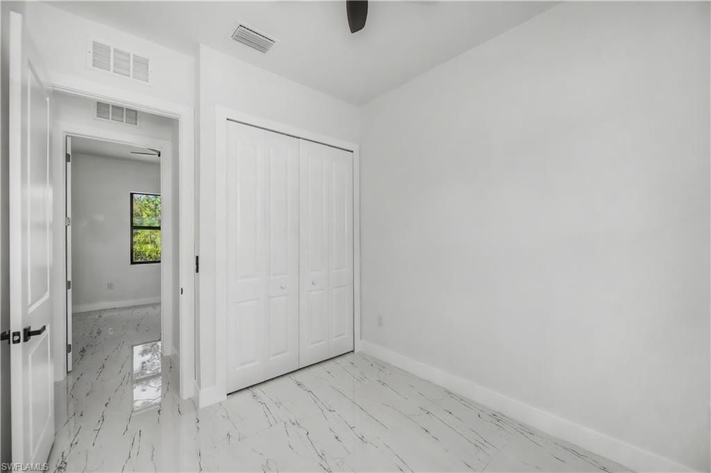 Spacious room featuring white walls, white bifold closet doors, and marble-look tile flooring