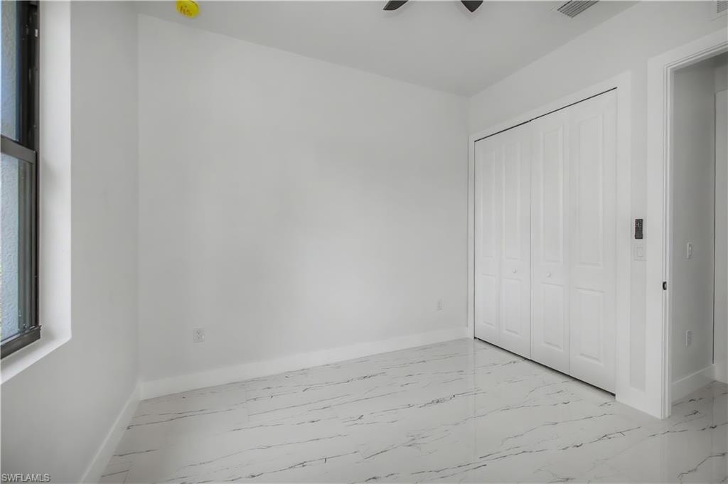 White walls, white trim, bi-fold closet doors, tile flooring, and a single window