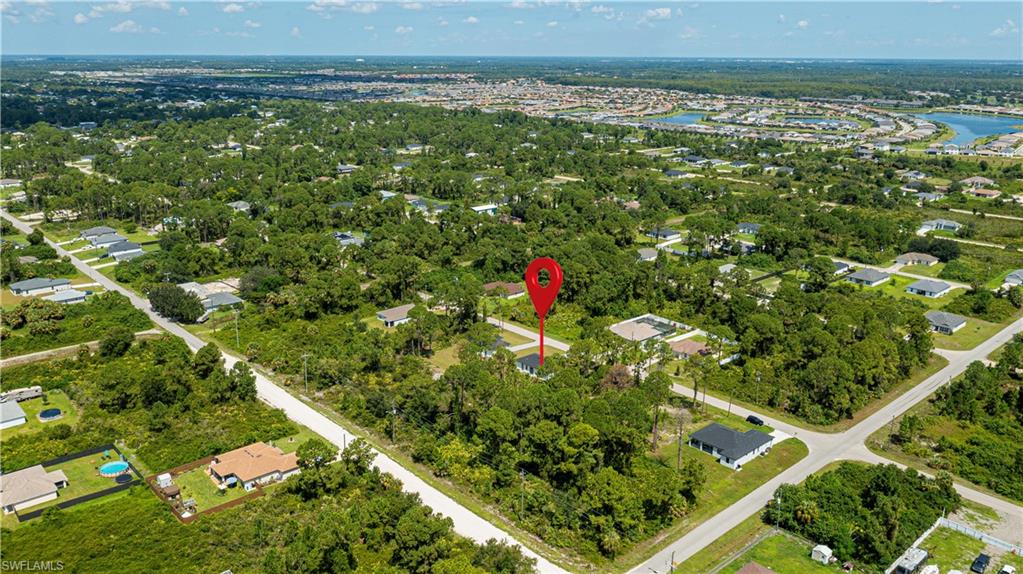 Aerial view of a residential area featuring established homes and undeveloped lots amidst abundant greenery