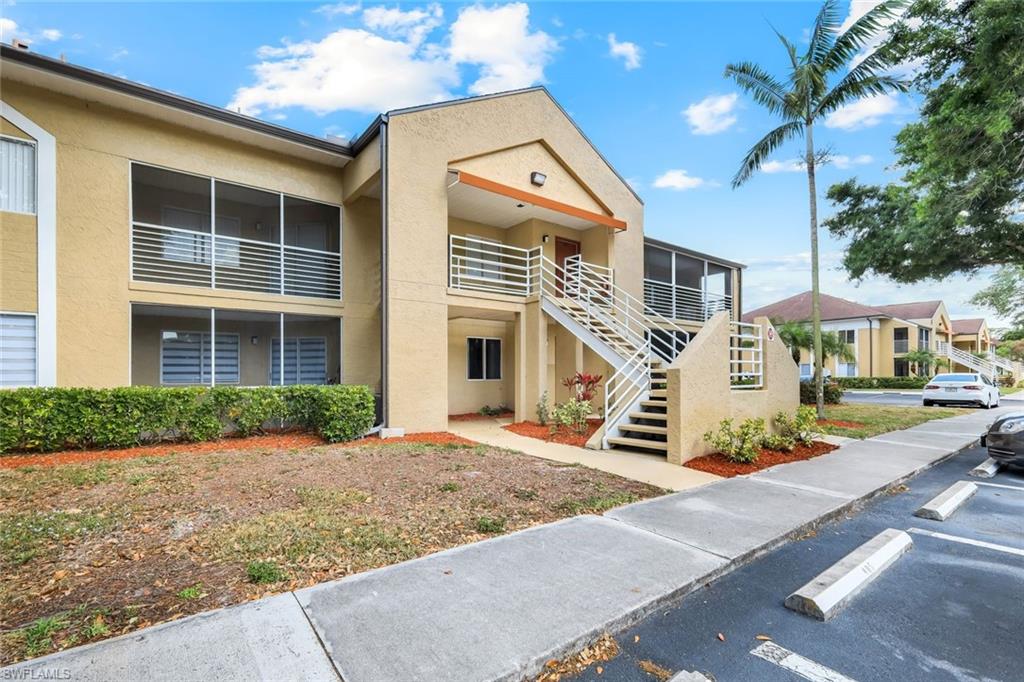 View of property featuring stairs and uncovered parking