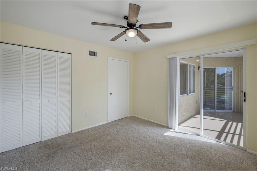 Unfurnished bedroom with access to outside, a closet, carpet floors, visible vents, and ceiling fan
