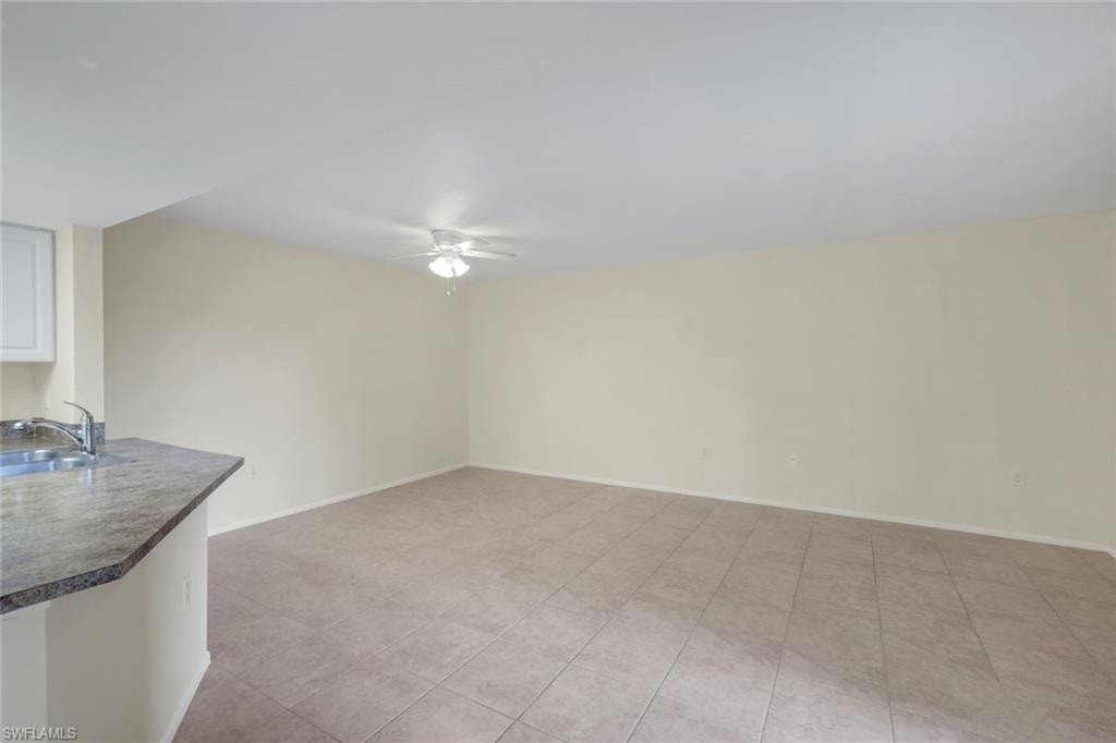 Empty room featuring a sink, baseboards, and a ceiling fan