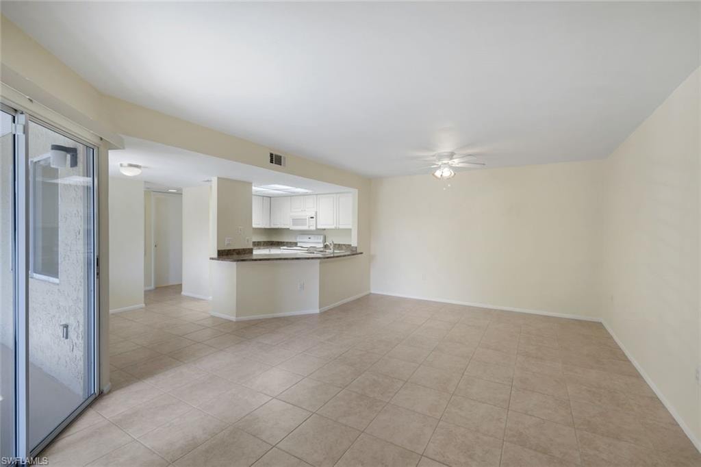 Unfurnished living room with light tile patterned floors, baseboards, a ceiling fan, and visible vents