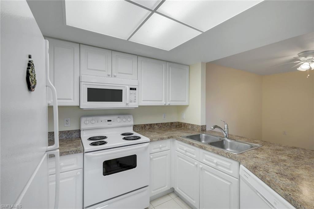 Kitchen featuring a sink, white cabinetry, and white appliances