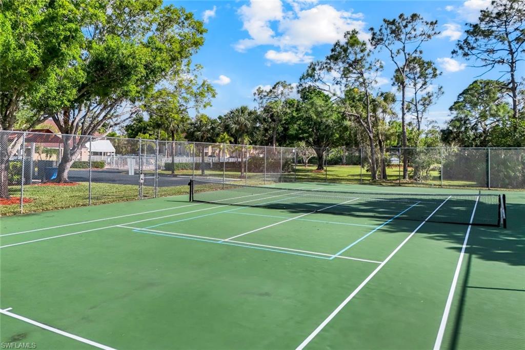 View of tennis court featuring fence and community basketball court