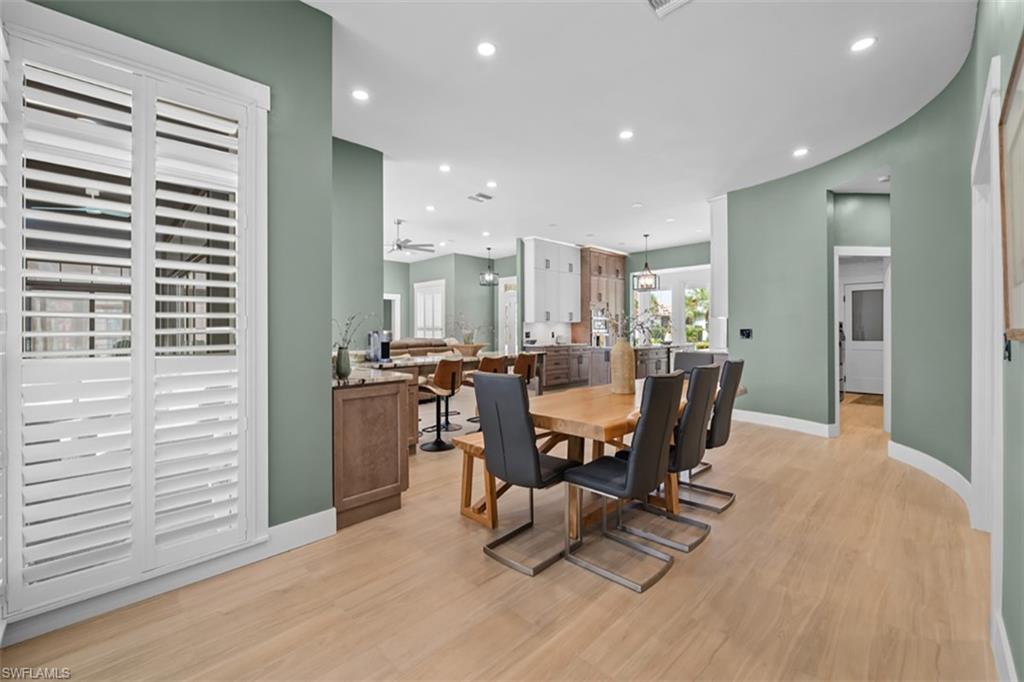 Wood-finish flooring throughout, curved wall feature, recessed lighting, and white plantation shutters