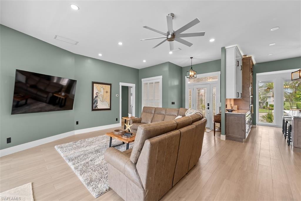 Recessed lighting, wood-finish flooring, ceiling fan, and decorative glass entry door with sidelights