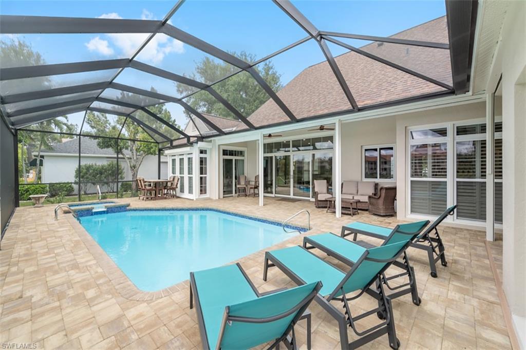 Screened-in outdoor living space with a built-in swimming pool and integrated spa