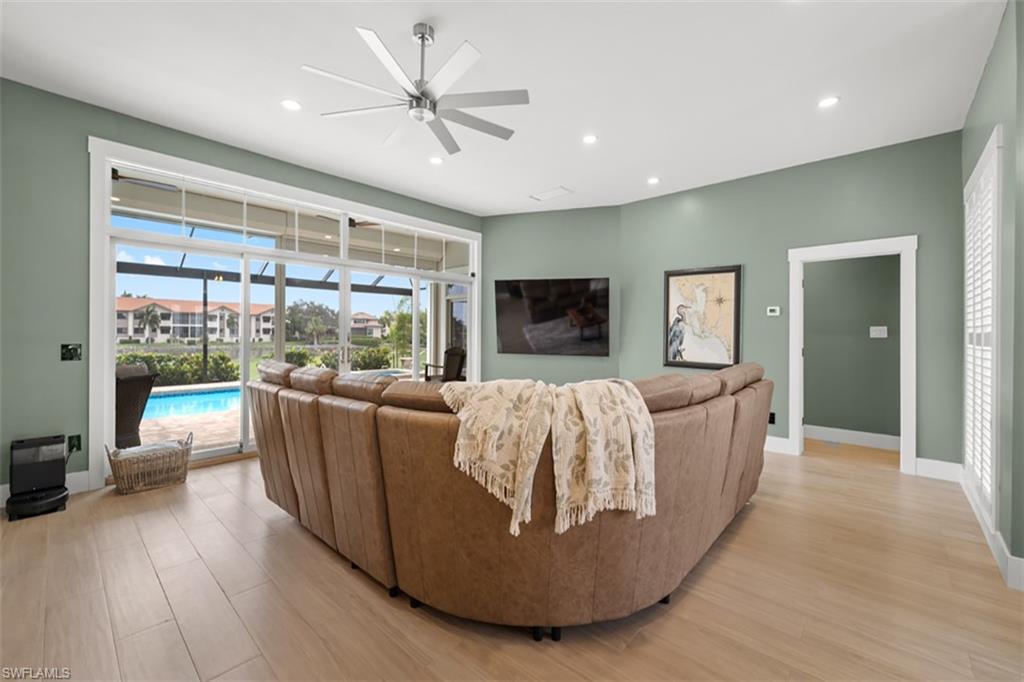 Expansive sliding glass doors, light wood-finish flooring, recessed lighting, ceiling fan, and plantation shutters