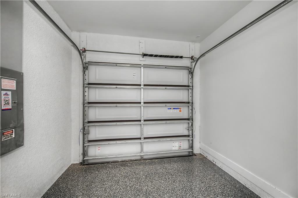 Garage space featuring a roll-up door, speckled flooring, and textured wall finishes