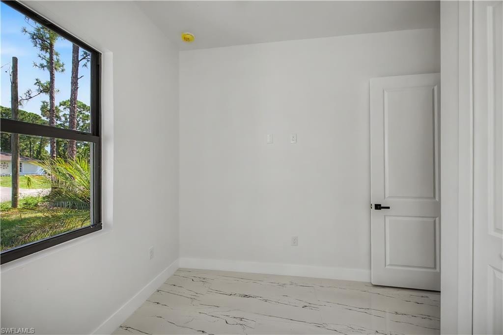 Recessed window with black framing, white walls, and marble-finish flooring