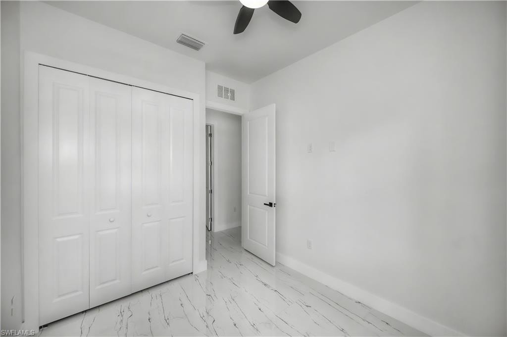 White bifold closet doors, light-toned walls, and a ceiling fan with dark blades
