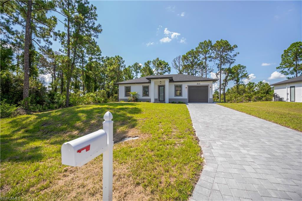 Contemporary facade with a dark gray garage door, light gray exterior accents, and a paver driveway