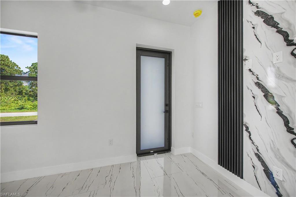 White walls, marble-patterned flooring, and a window with black trim