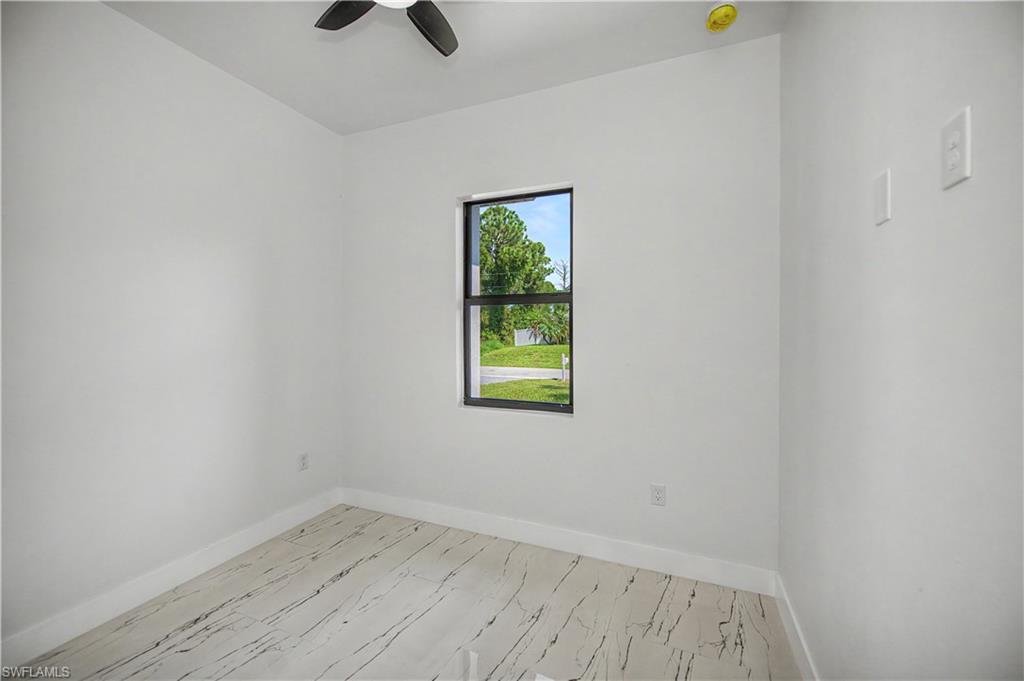 Light-filled room featuring a single window, a ceiling fan, and wood-finish flooring